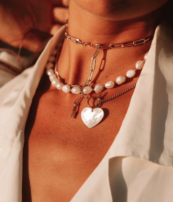 woman wearing a pearl and gold necklace with a pearl heart