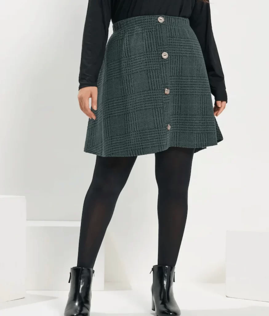 short aline skirt with buttons down the front in green with black short boots and black opaque tights