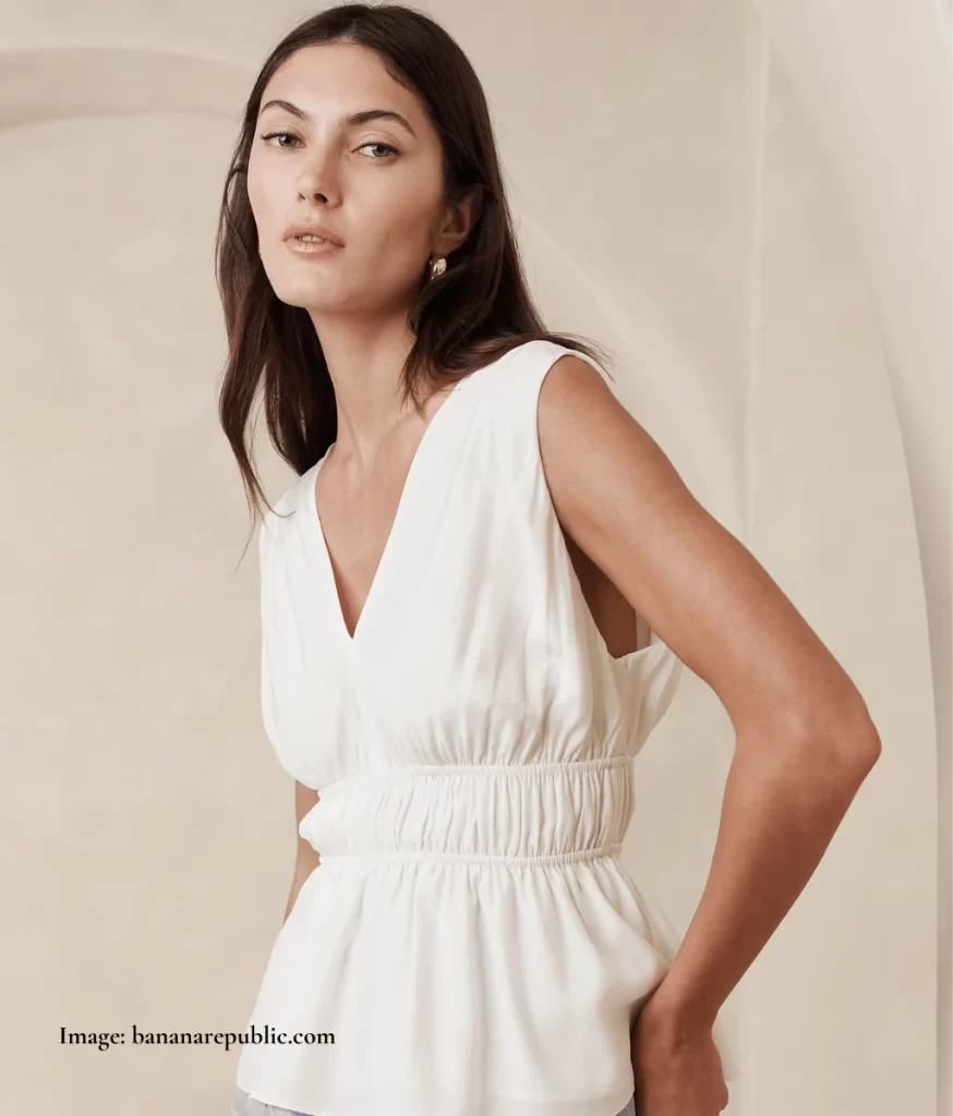 model wearing a cream gathered waist top with a v-neck and peplum