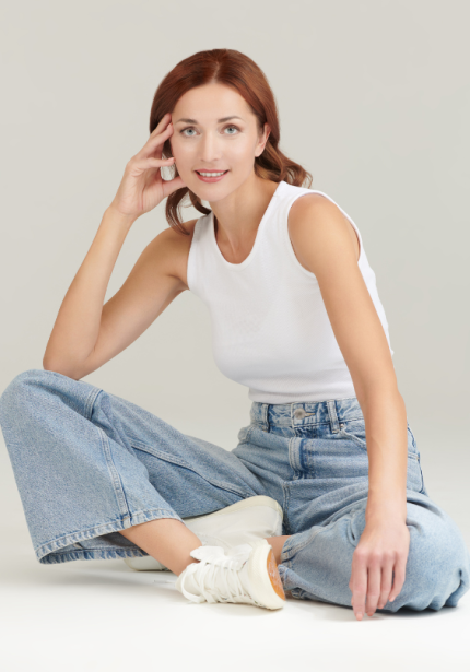 pretty lady looking at camera wearing blue jeans and a white singlet top